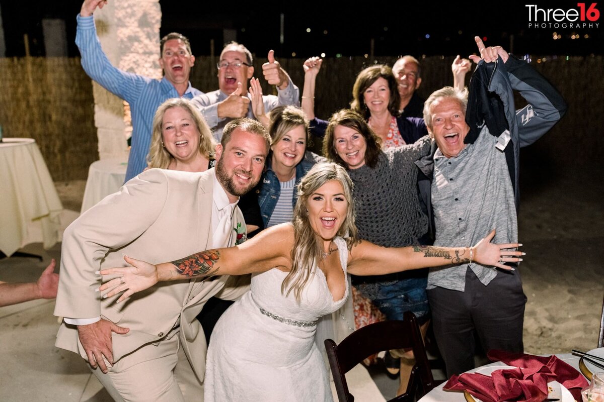 Fun photo of Bride and Groom posing with a group of guests during the reception