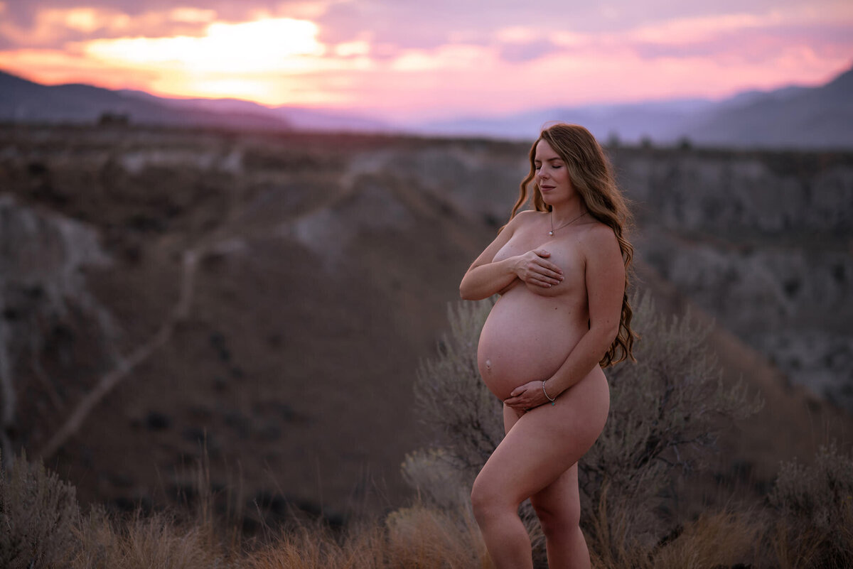 Brittany Danielle captures this beautiful blue hour maternity portrait of a nude pregnant woman. She closes her eyes and holds her belly while covering her breasts