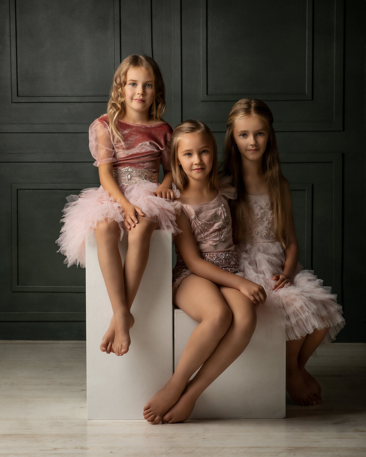 Three little sisters dressed in tulle dresses posing for the canon camera in London studio