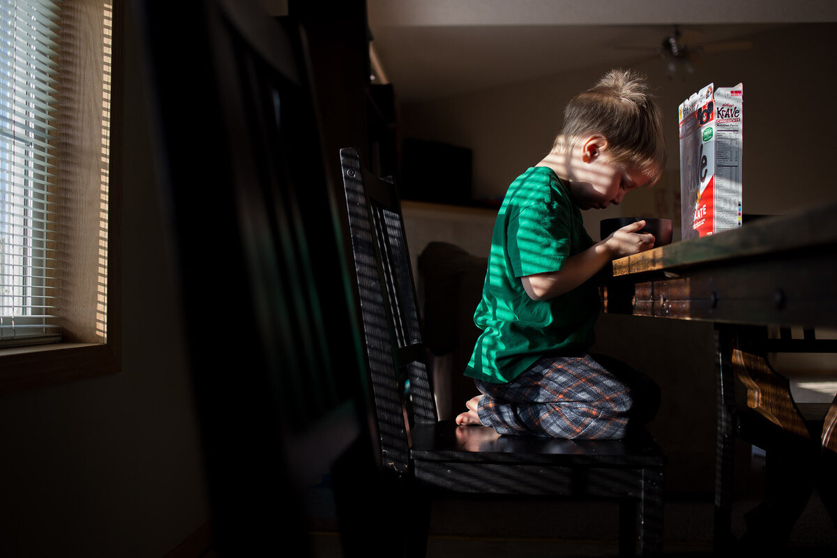 toddler sitting on knees at dining table