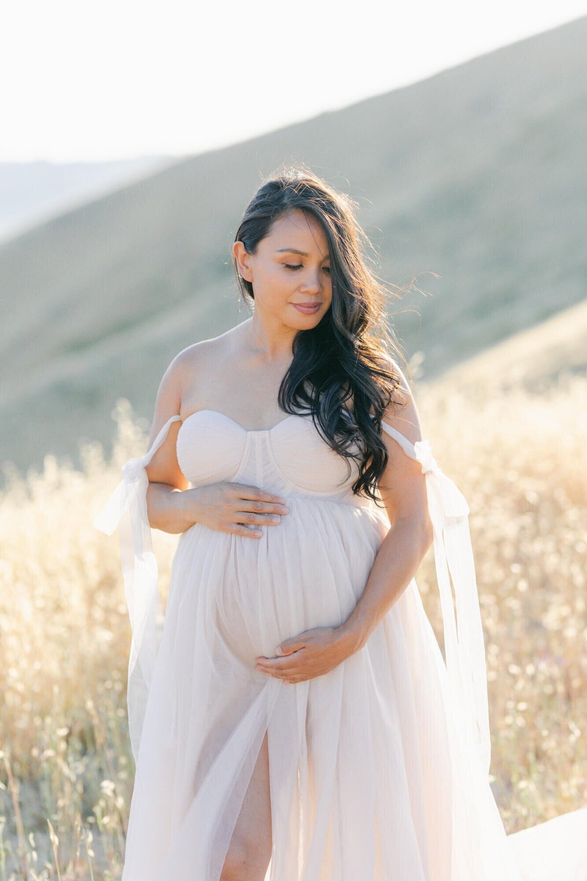 Pregnant woman framing her belly in a tulle dress taken by San Francisco Maternity Photographer Laurel Smith.