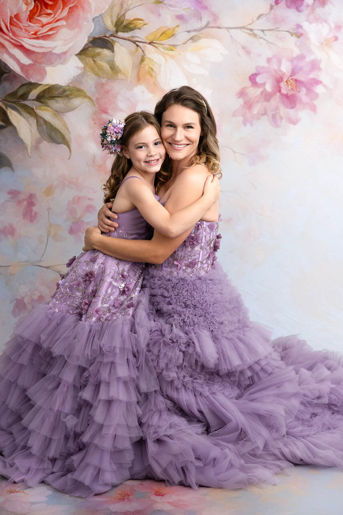 Close up of girl with flower crown and mother hugging against fine art backdrop