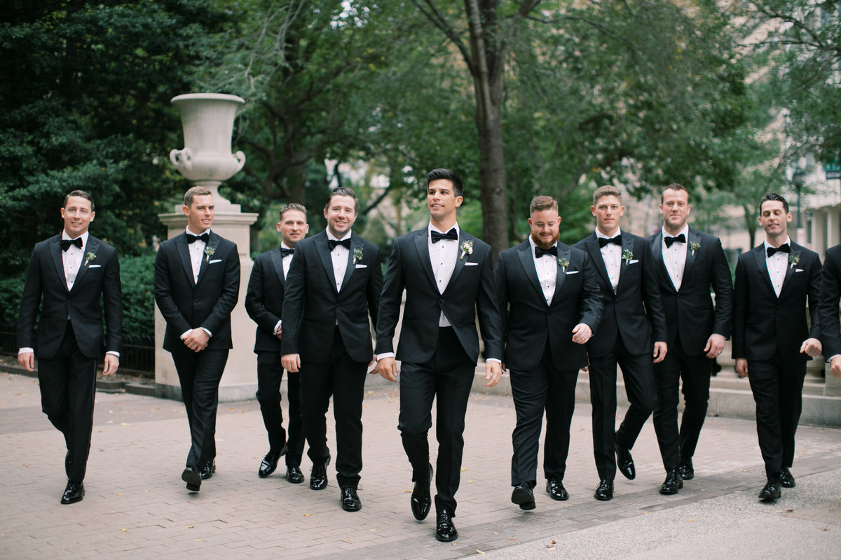 groom walking with groomsmen during outdoor formal portraits