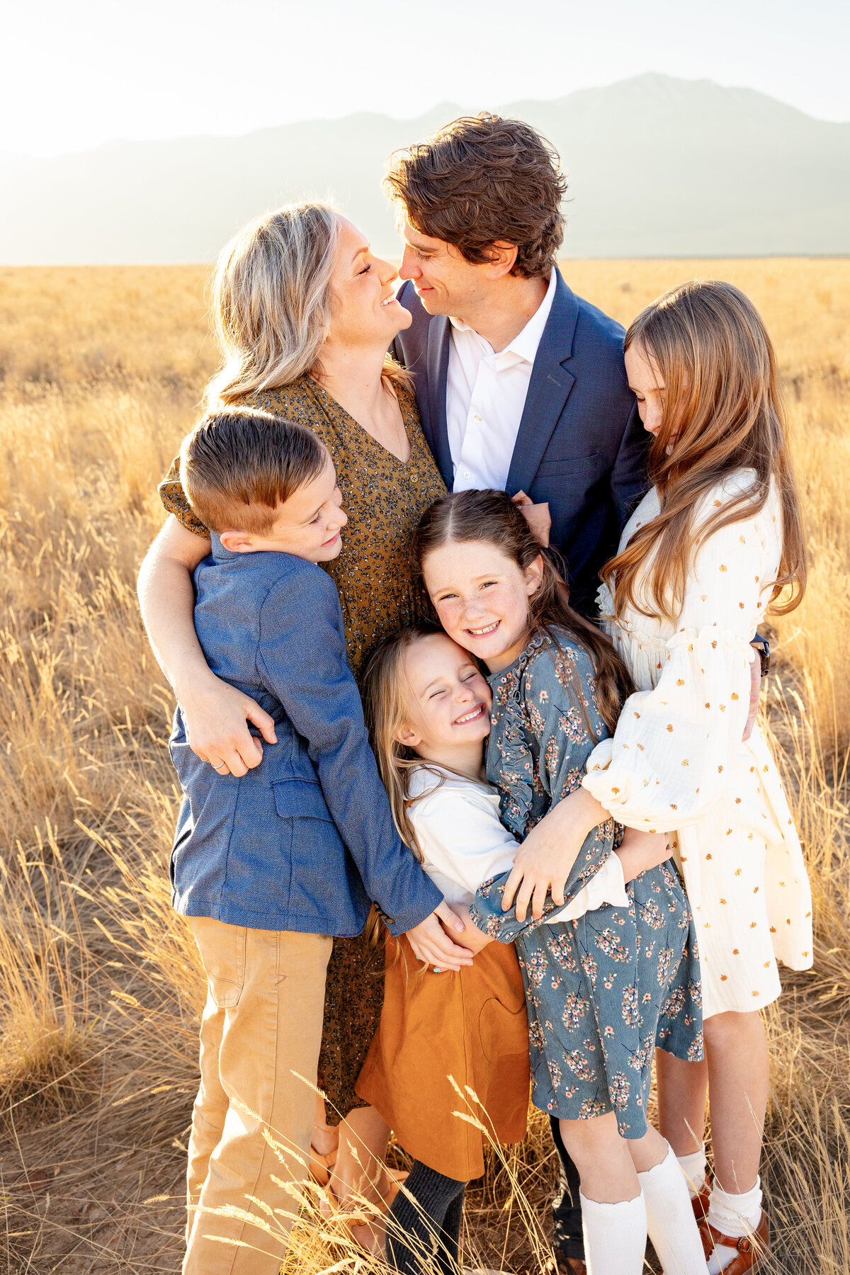 The family of six shares a group hug as the mother and father gaze lovingly into each other's eyes.