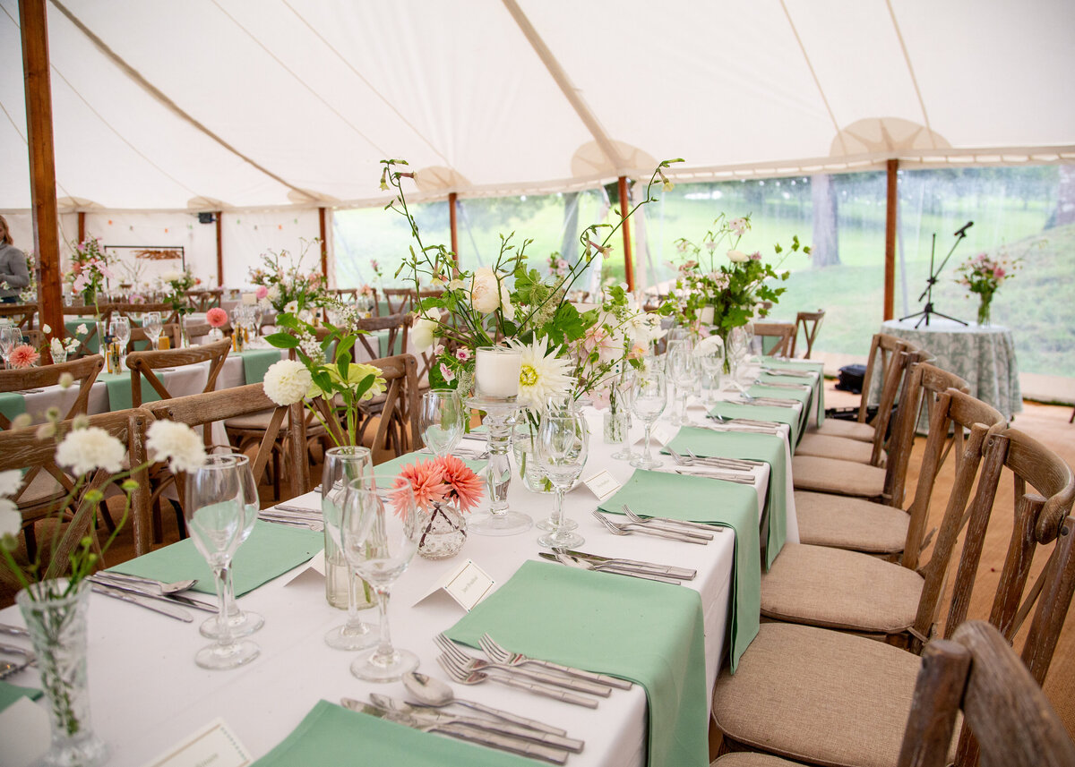 A mixture of bud vases and candles on the tables for this pole marquee wedding