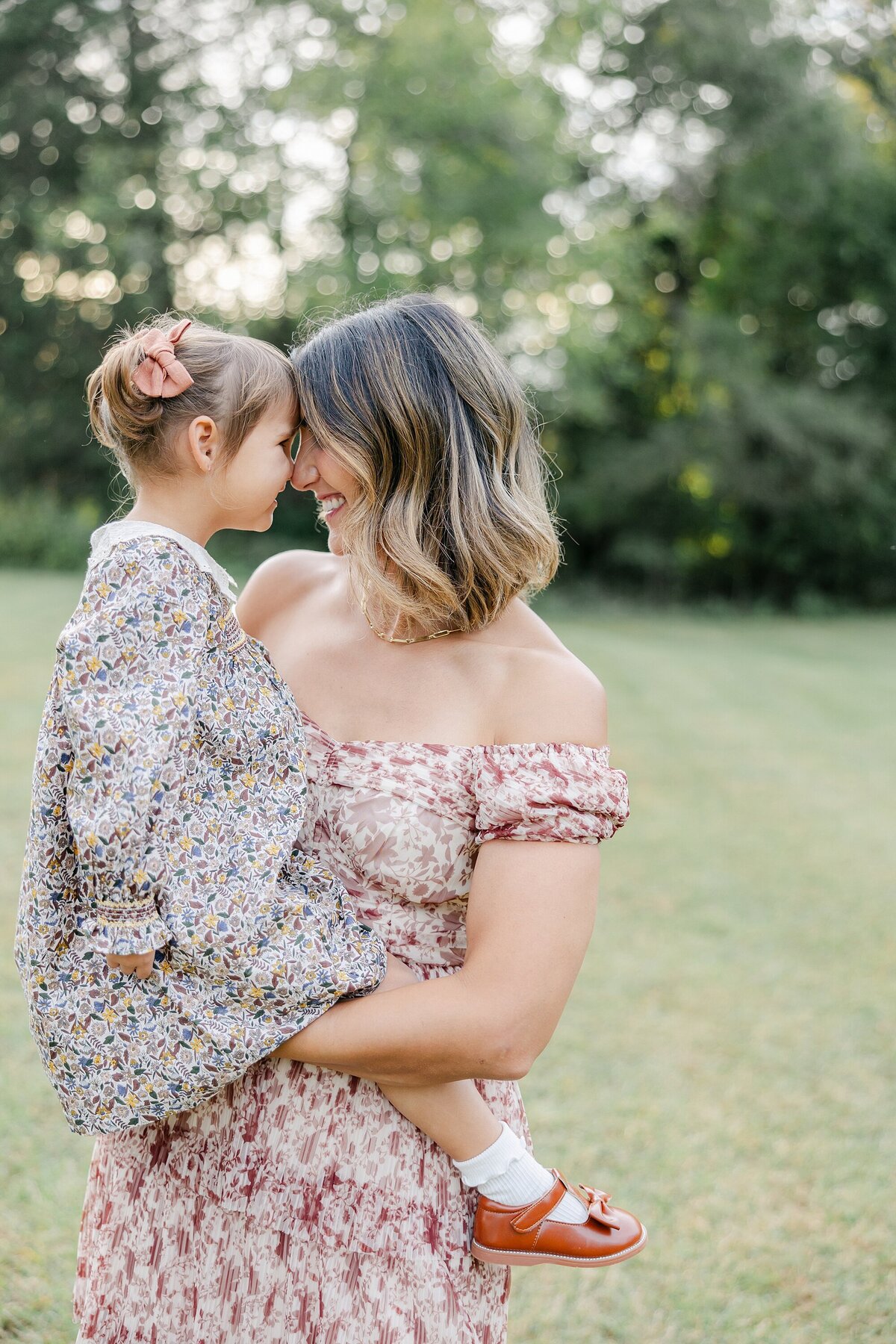 mom holding litte girl and forehead to forehead
