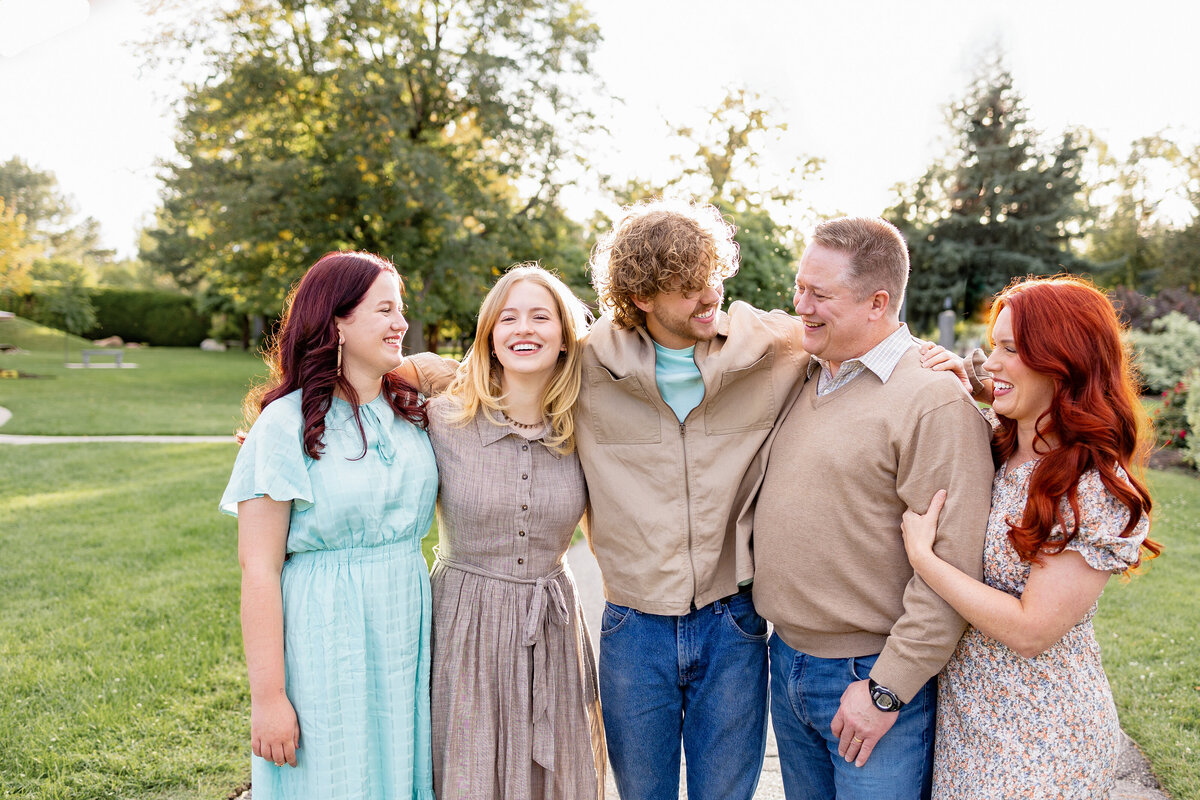 A happy family of five laughing together at the International Peace Gardens in Salt Lake City, Utah, as they enjoy a candid moment in the sun