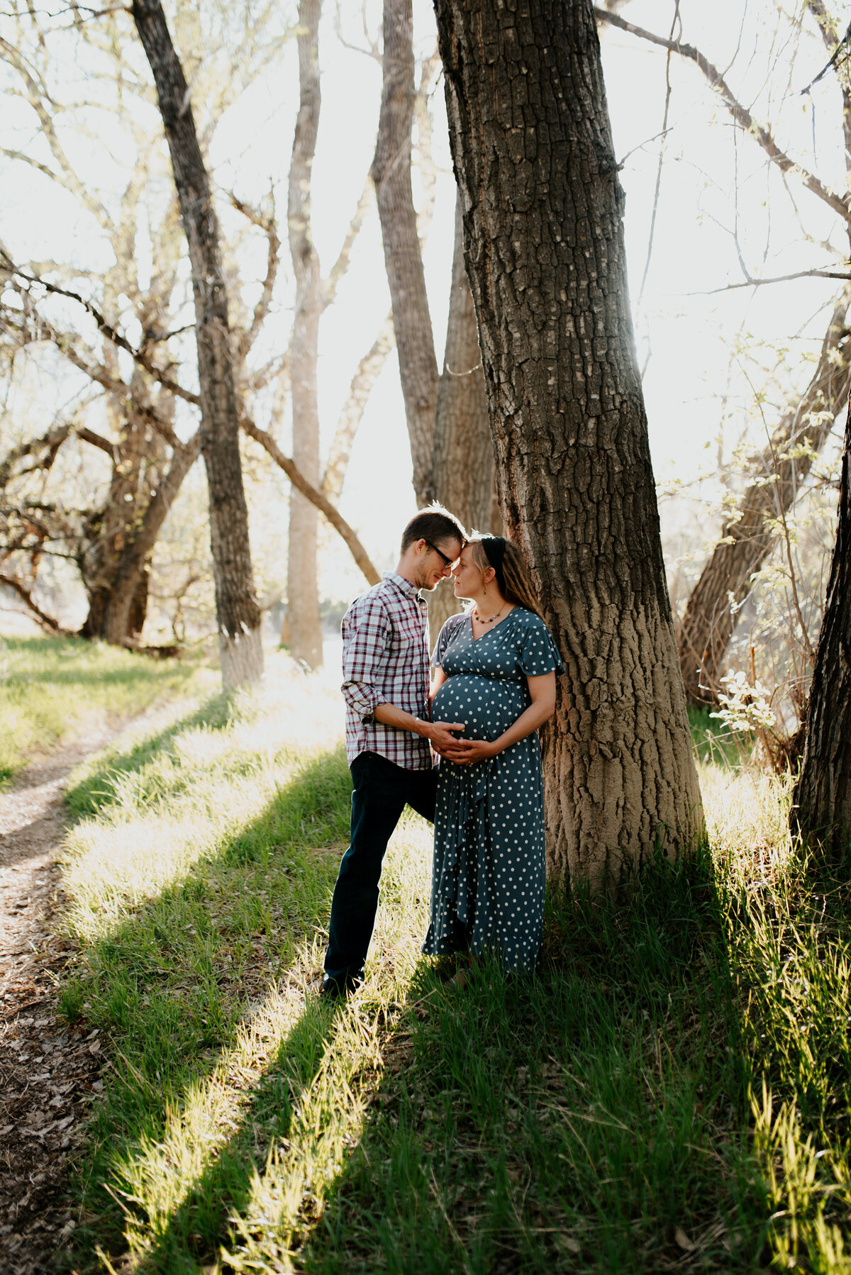 maternity photo shoot with dad holding moms pregnant belly near poudre river in fort collins