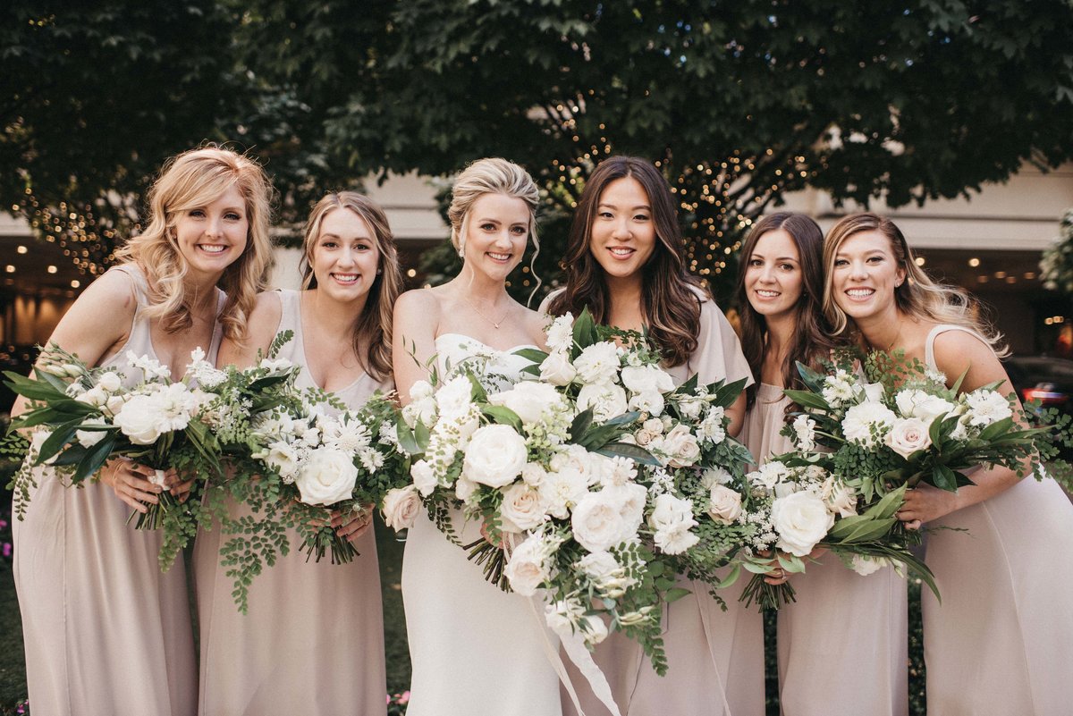bridal party wearing champagne dresses holding white and green wedding bouquets