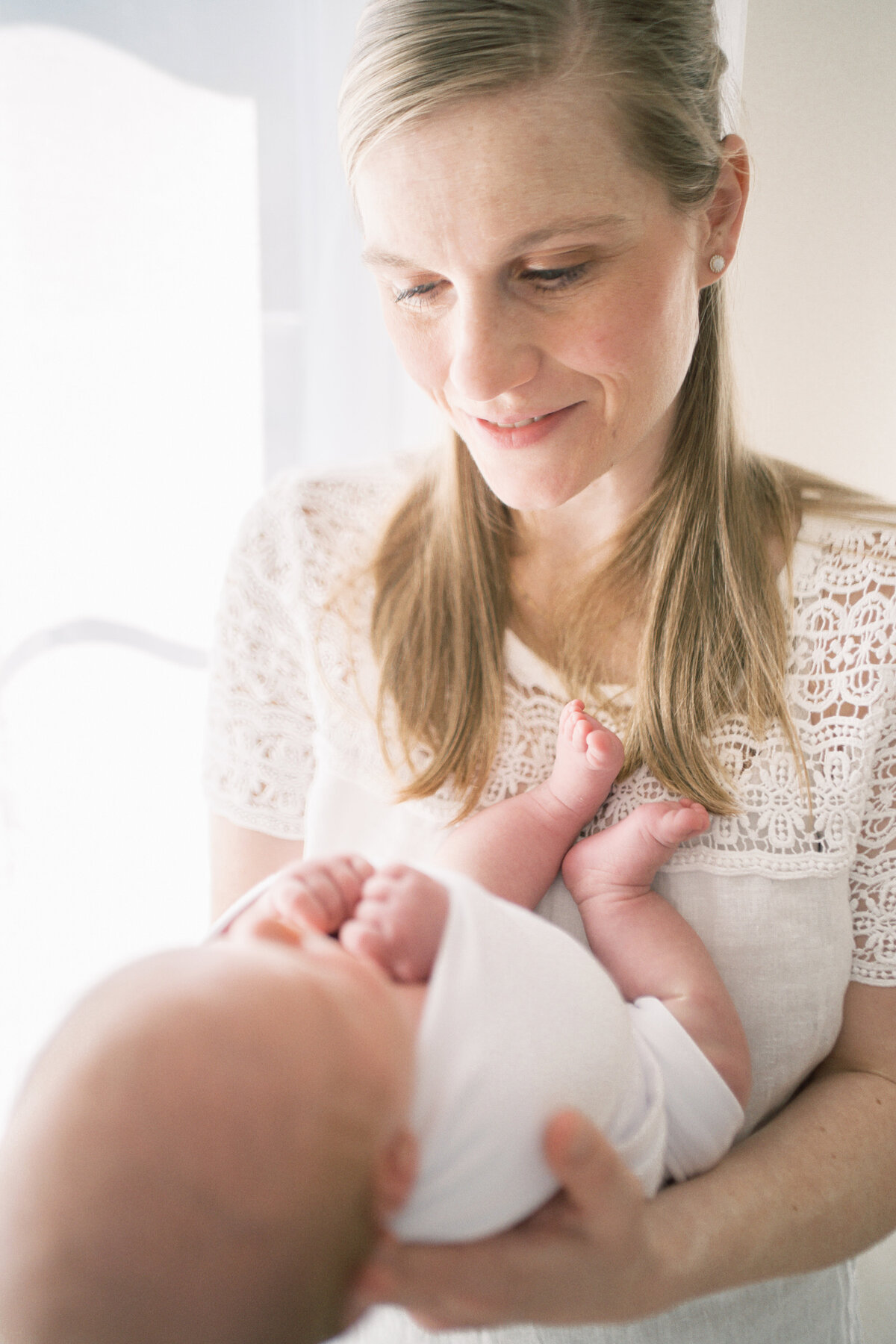 Mother cradling her newborn baby in her nursery by Oklahoma City Newborn Photographer Courtney Cronin