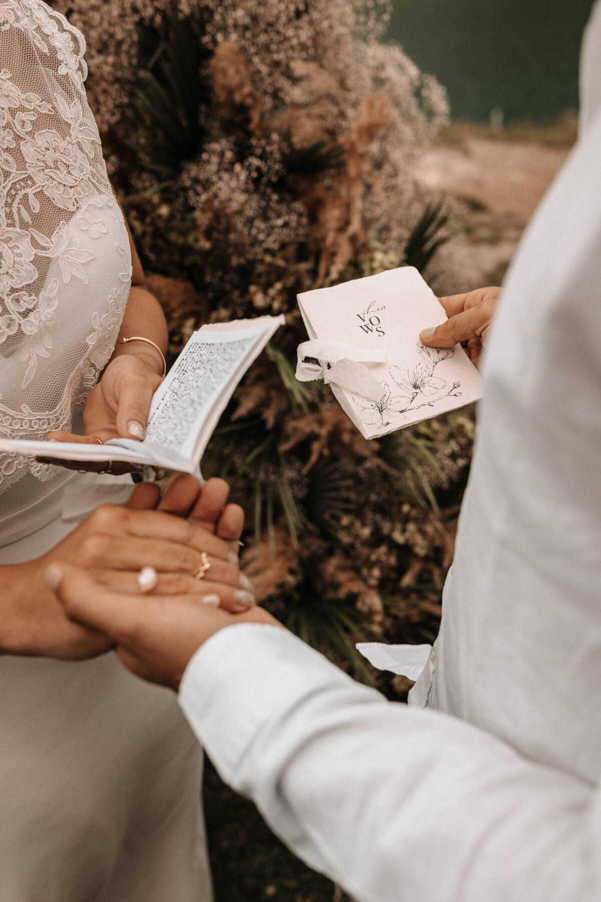 Nahaufnahme von Hochzeitspapeterie und Händen vom Brautpaar
