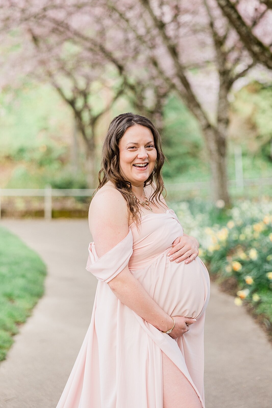 smiling mom holding belly for maternity photos