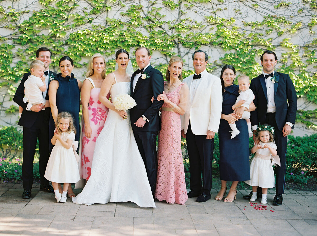 Newlyweds and their wedding party pose for a photo, surrounded by nature.