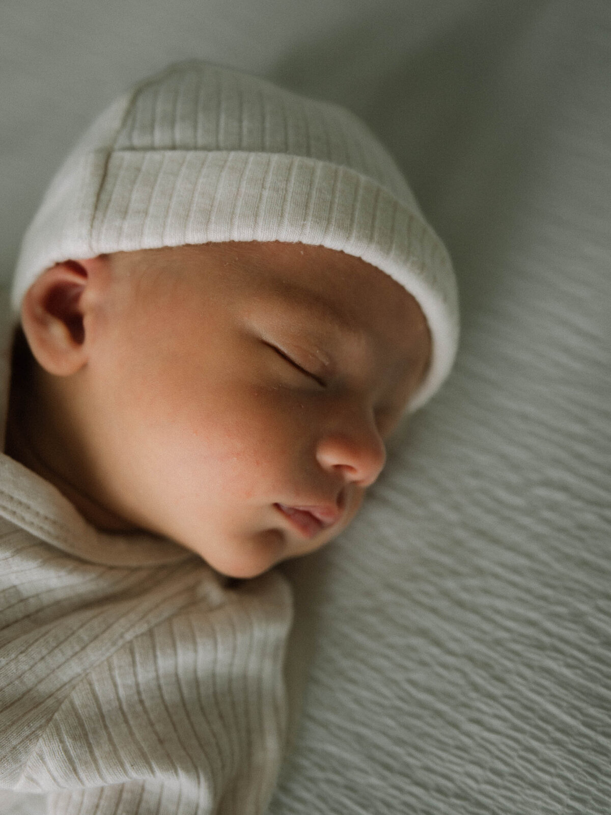 Solo newborn portrait with a knit hat captured during a lifestyle baby photography session.