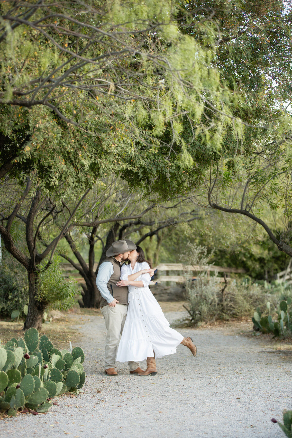 Couple at the Drover Hotel in Fort Worth during their country-style engagement session, he twirls her into a kiss.