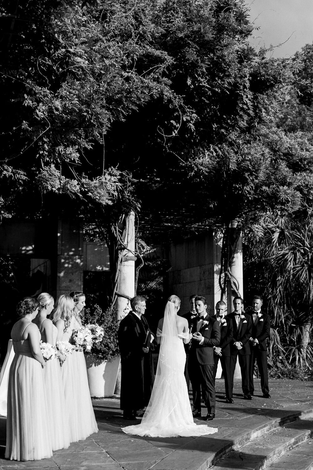 Bride and groom holding hands at ceremony altar Dallas Arboretum wedding veil