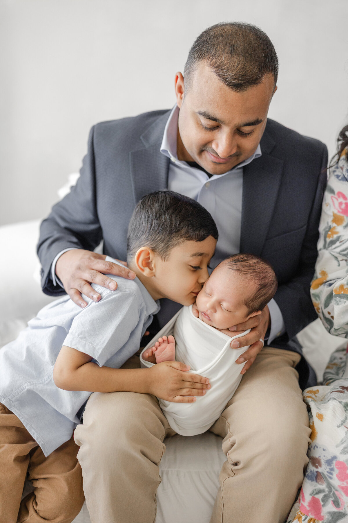 Newborn baby boy cuddled by big brother during natural light luxury portrait session in Tampa studio