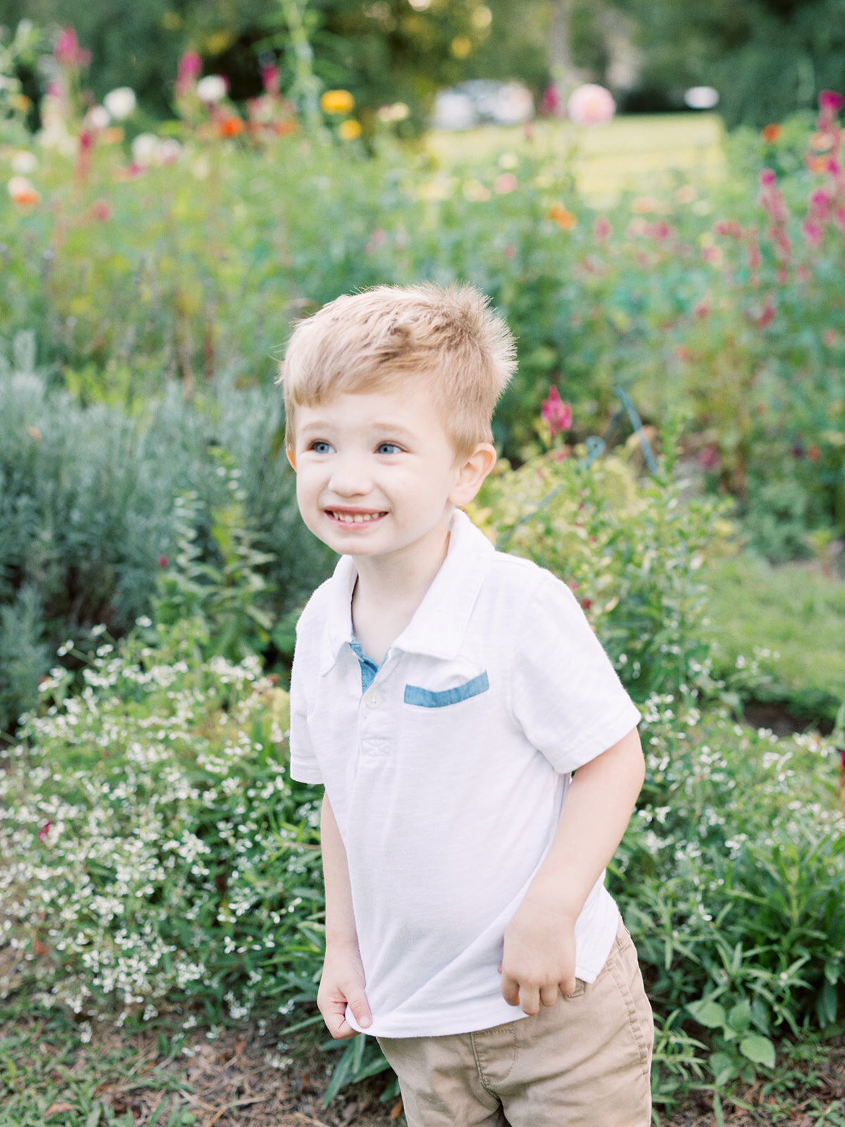 A young boy smiling in a garden during a Richmond family photography session by Katie Stansfield Photography.