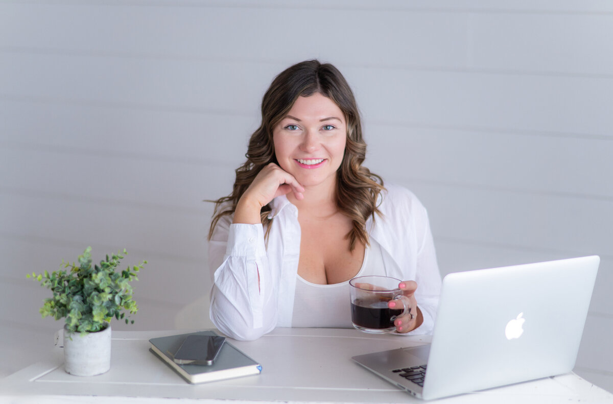 Sarah Hawk, tech educator, and personal growth advocate, posing at desk with laptop and coffee