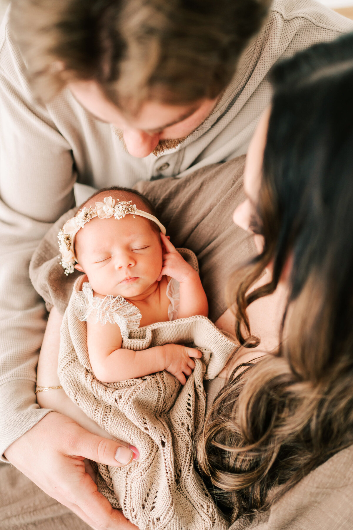Springfield MO newborn photographer captures parents holding sleeping baby girl in floral crown