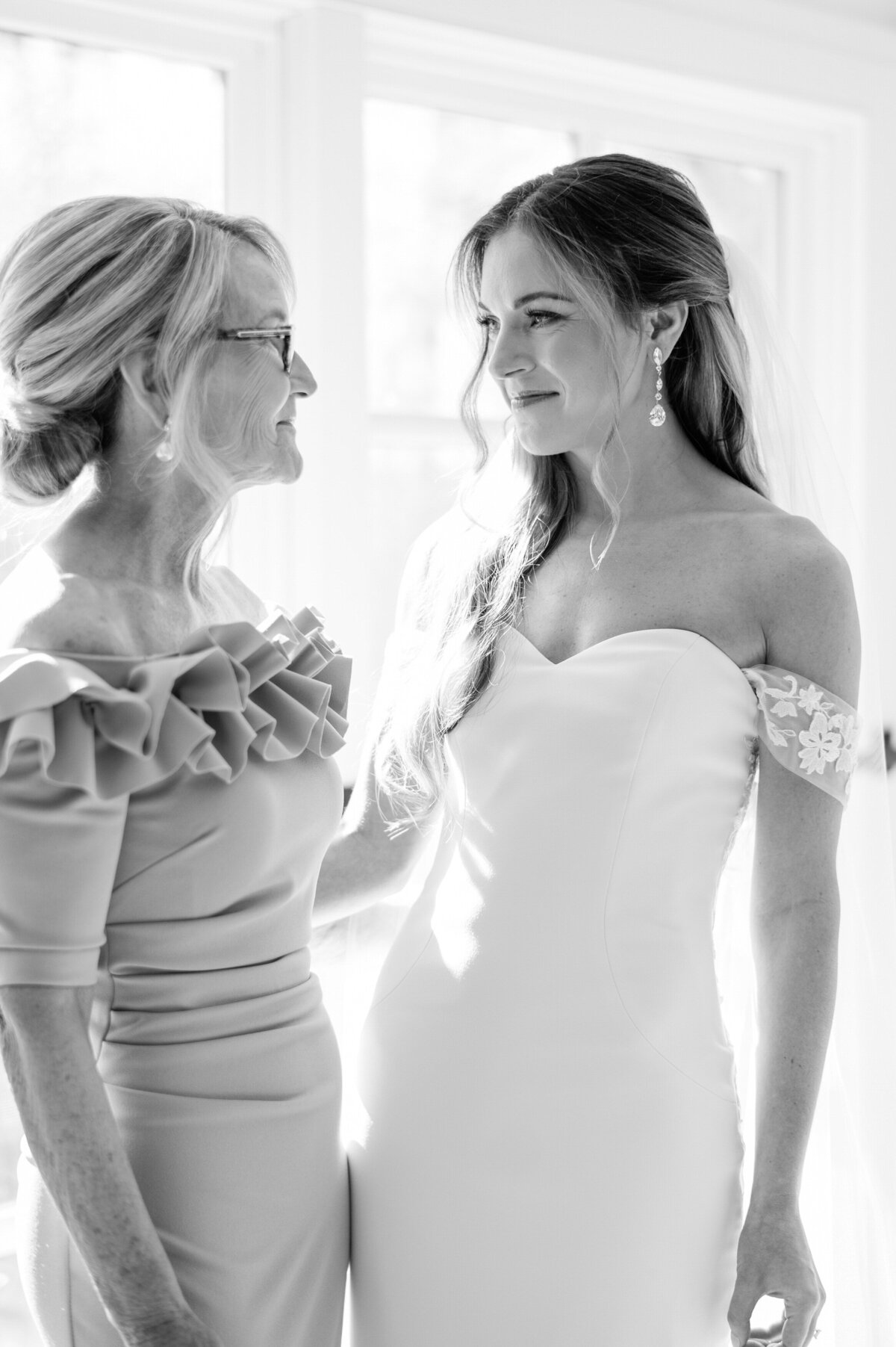 Bride and her mother smile at each other