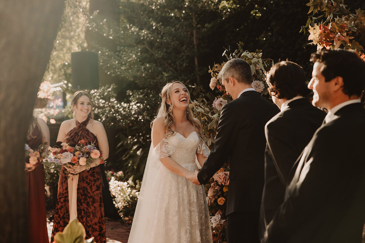 A couple holding hands and laughing during their wedding ceremony 