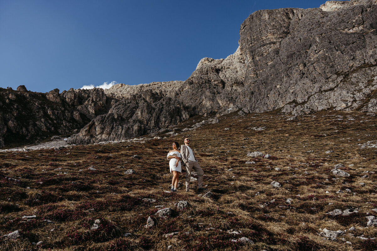 Bride and groom hiking together along mountain ridge