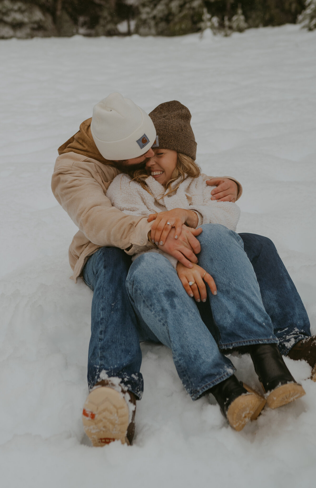 couple sitting in the snow cuddling and holding hands