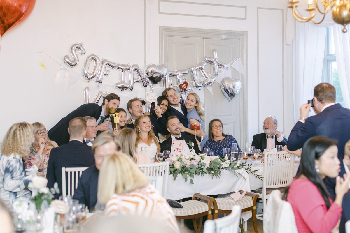 Bröllopsgäster och bröllopspar tar gruppbild under middagen på Schenströmska