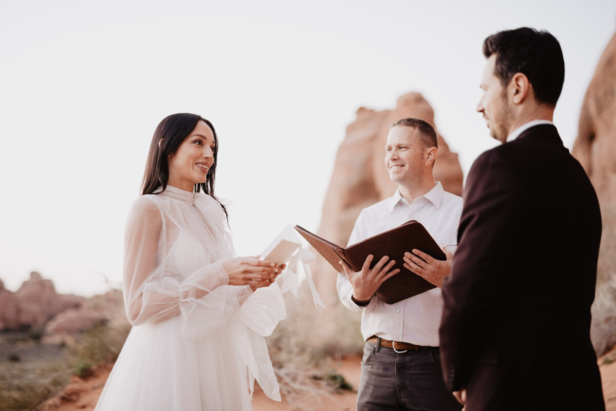 Utah elopement photographer captures bride reading vows during Arches National Park elopement