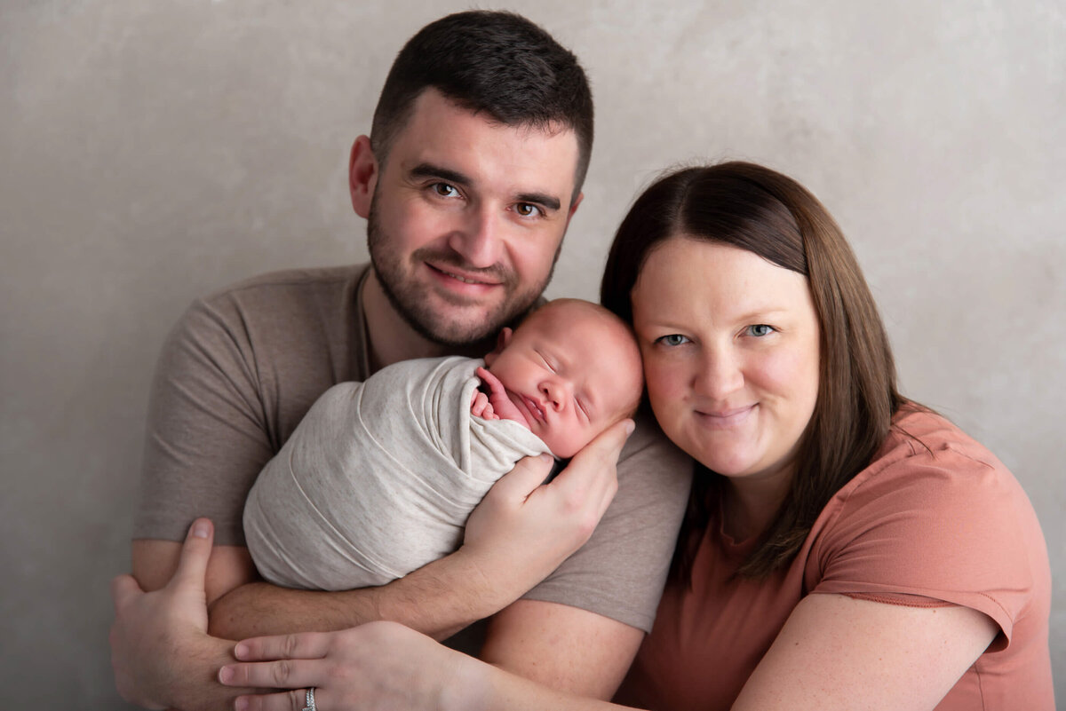 mom and dad holding baby for their newborn photography session Burlington, Ontario.