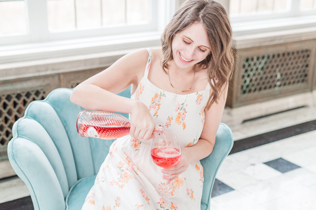 woman pouring sweet wine sitting on a light blue couch