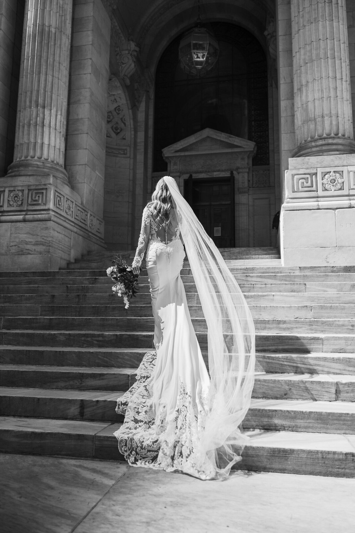 bride walking up steps with veil flowing