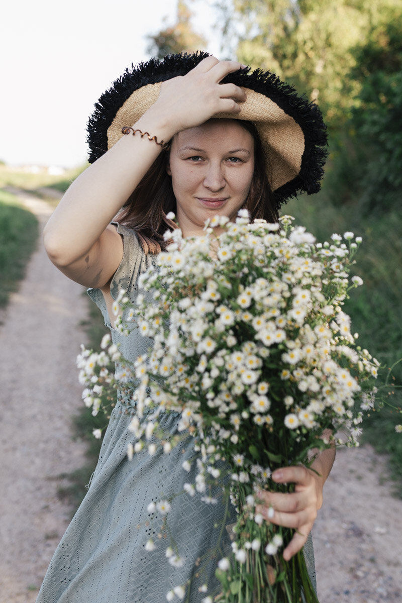 Young woman with a sun hat holding wild white flowers