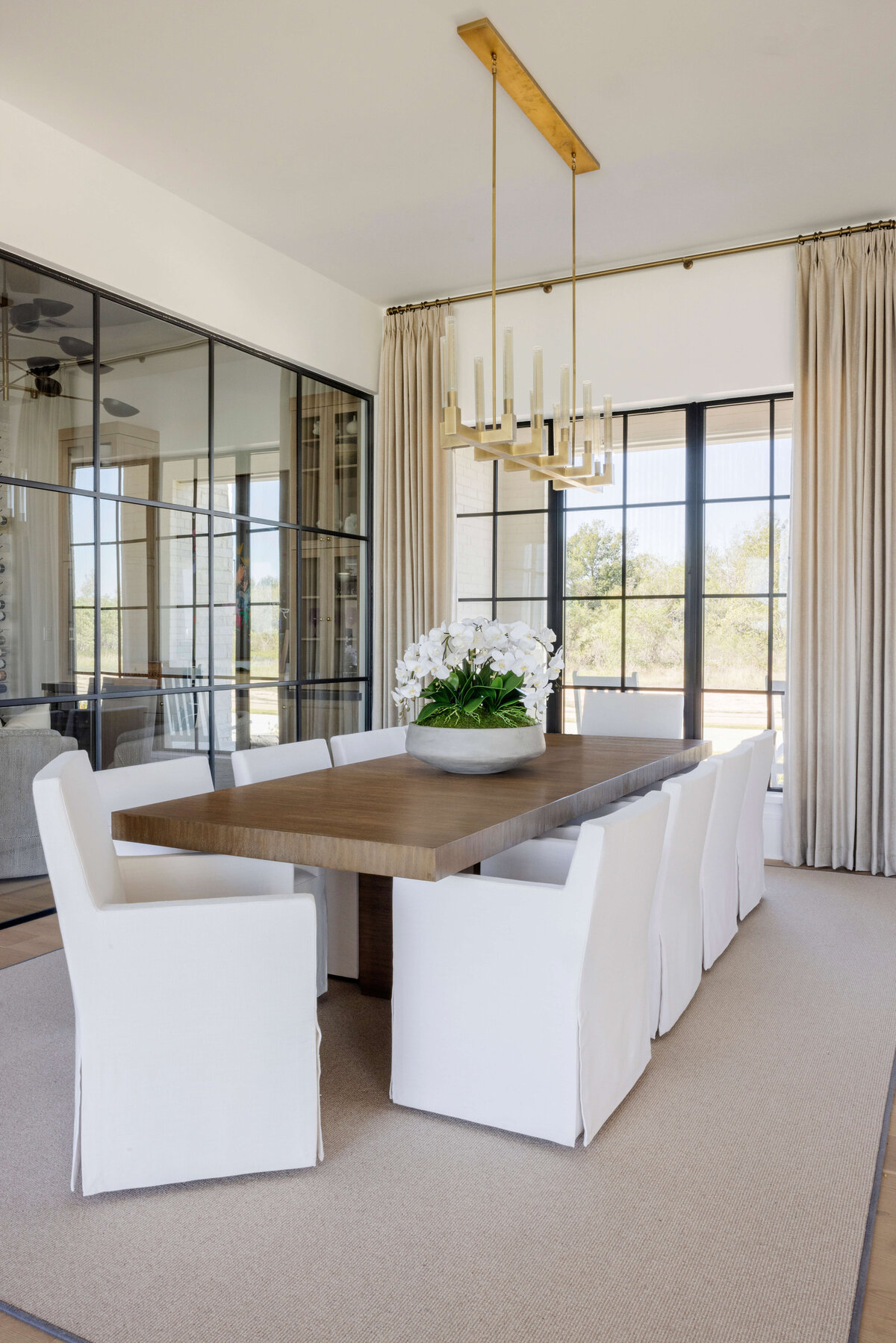 oyster creek studios hughes gold lighting in dining area with white dining room chairs and wooden table