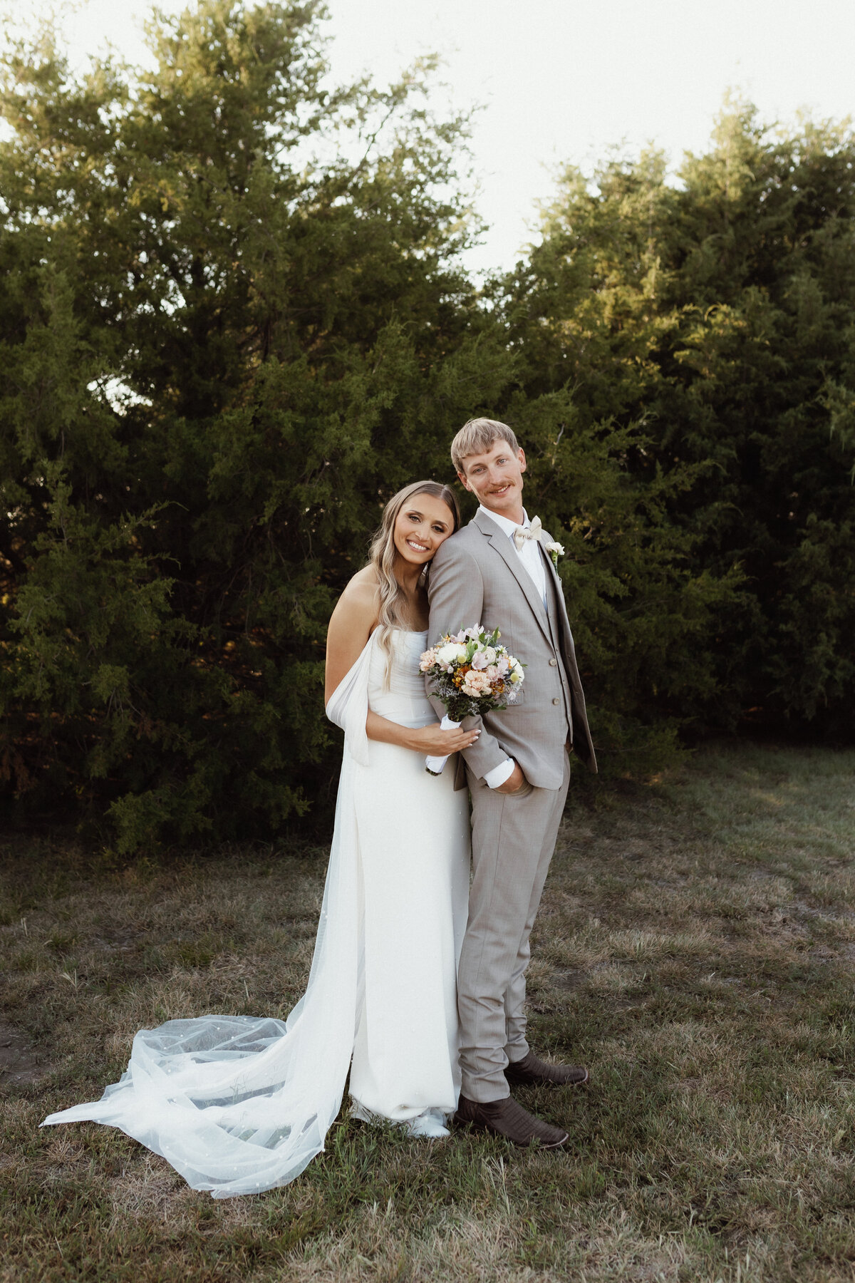 Kansas Wedding Photographer| Bride and groom poses in a field for their bridal photoshoot.
