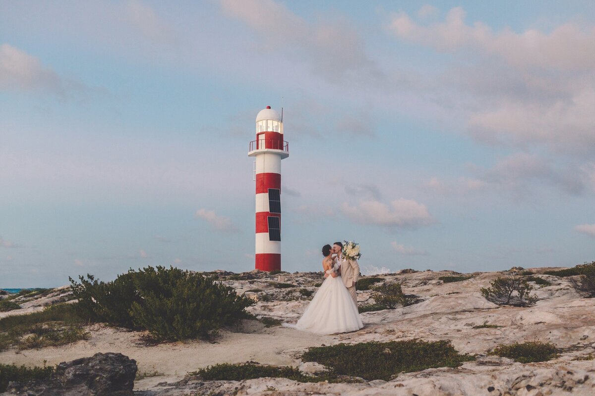 Bride and groom kissing in front of lighthouse at Hyatt Ziva in Cancun