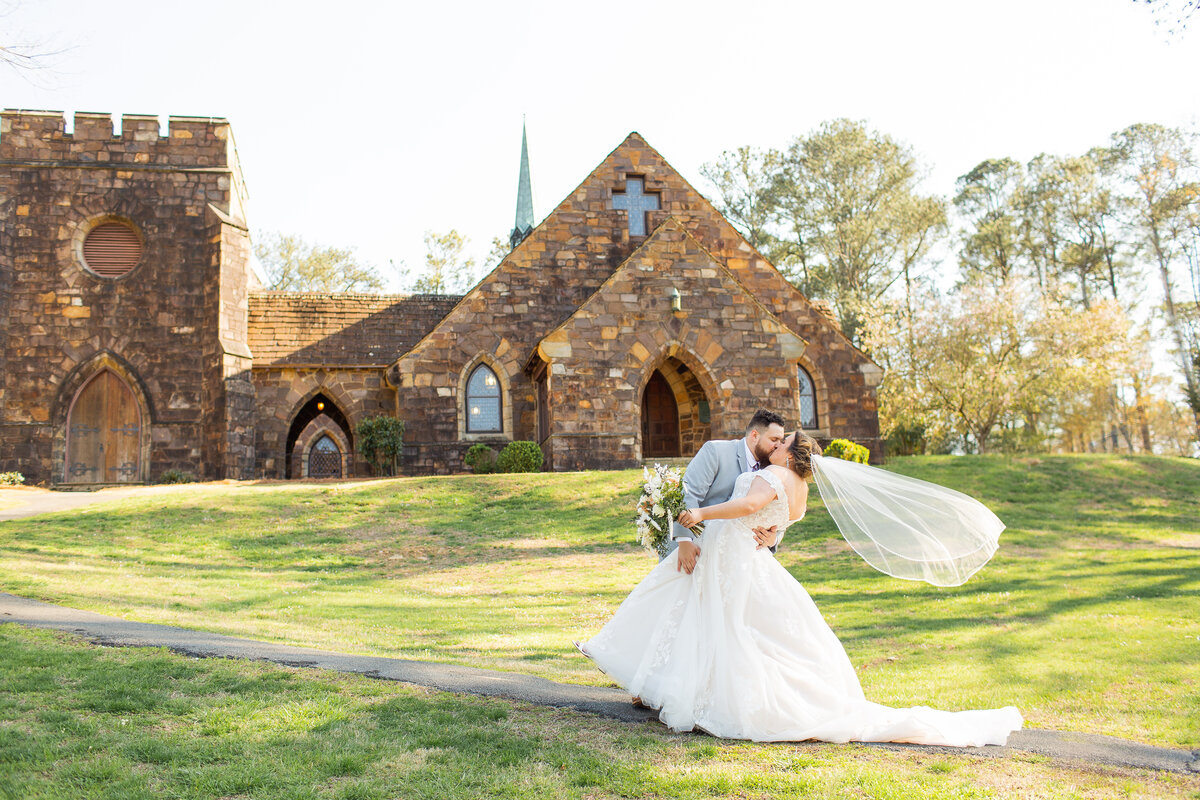 bride and groom kissing in front of a  stone church