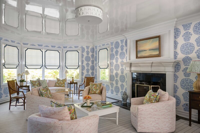 Sitting room interior with floral upholstered armchairs, round stone cocktail table and soft cream drapery