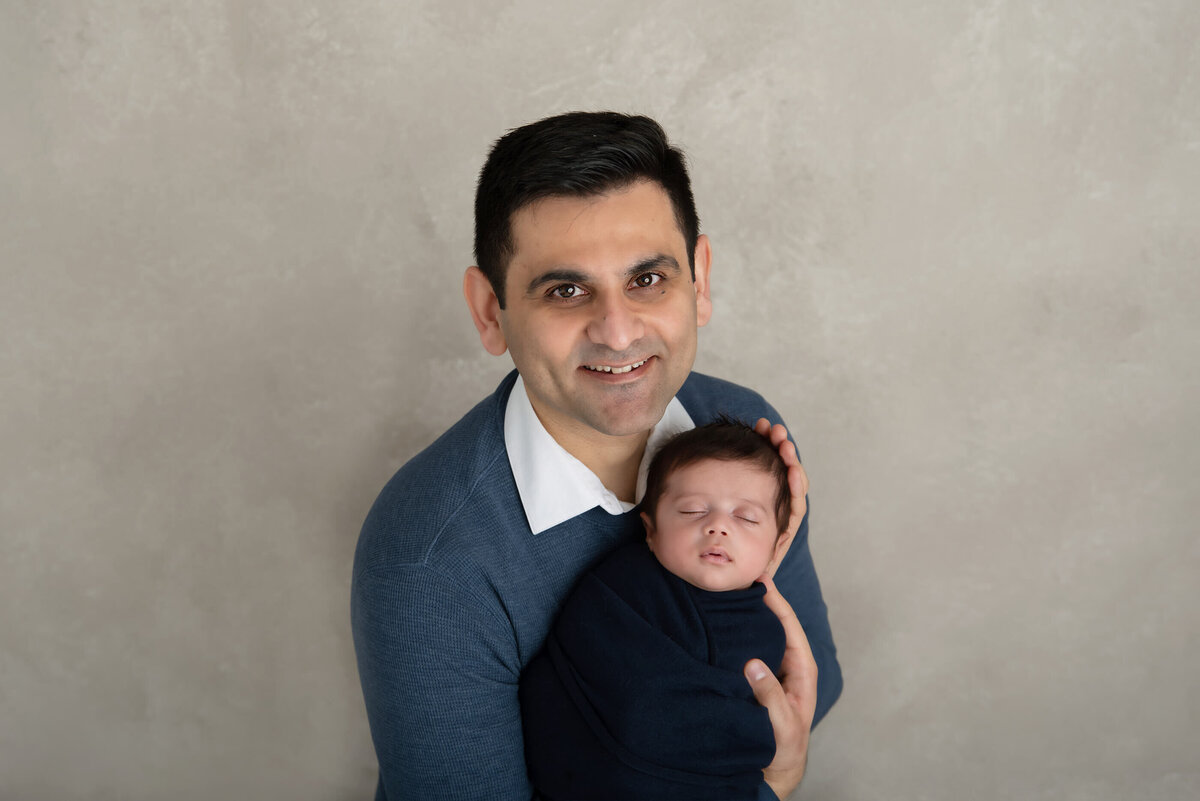 dad holding newborn baby boy wrapped in blue for his Burlington, ON newborn photography session