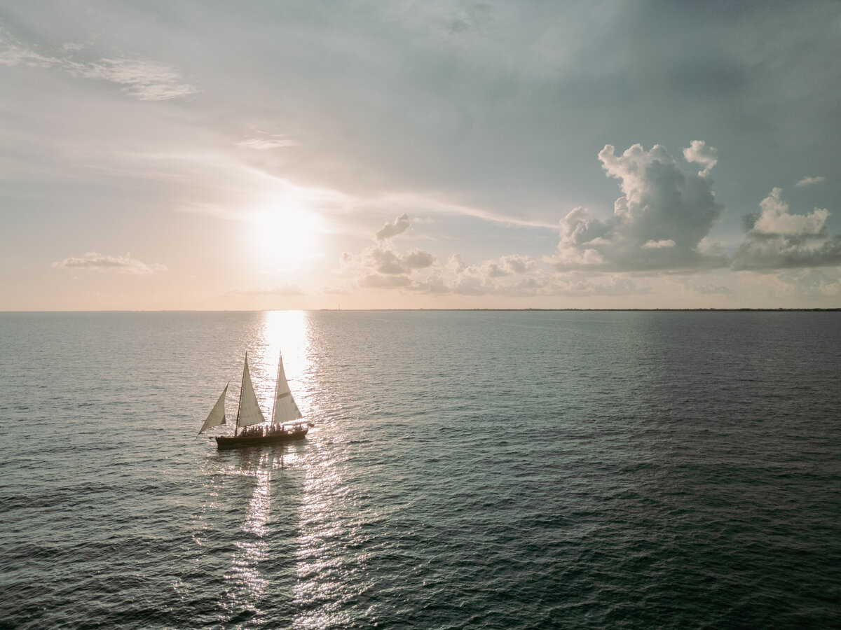 Sail boat sails at sunset  over blue waters