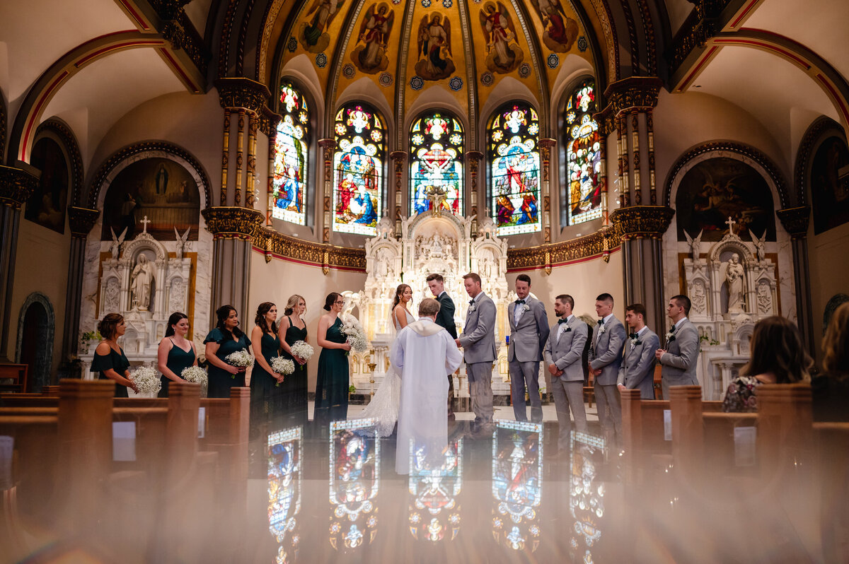 stained glass is reflected at a church during a wedding ceremony