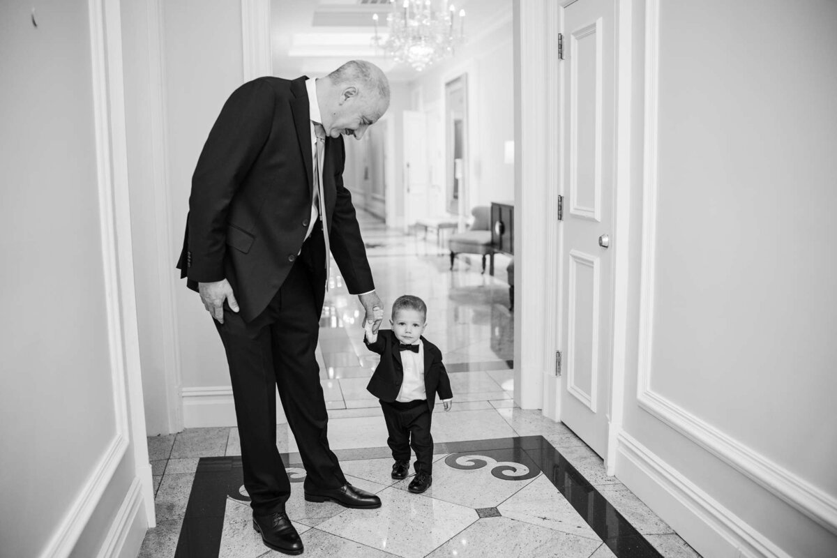 Ring bearer being escorted by his grandfather the father of the groom photographed by Palm Beach Wedding photographers