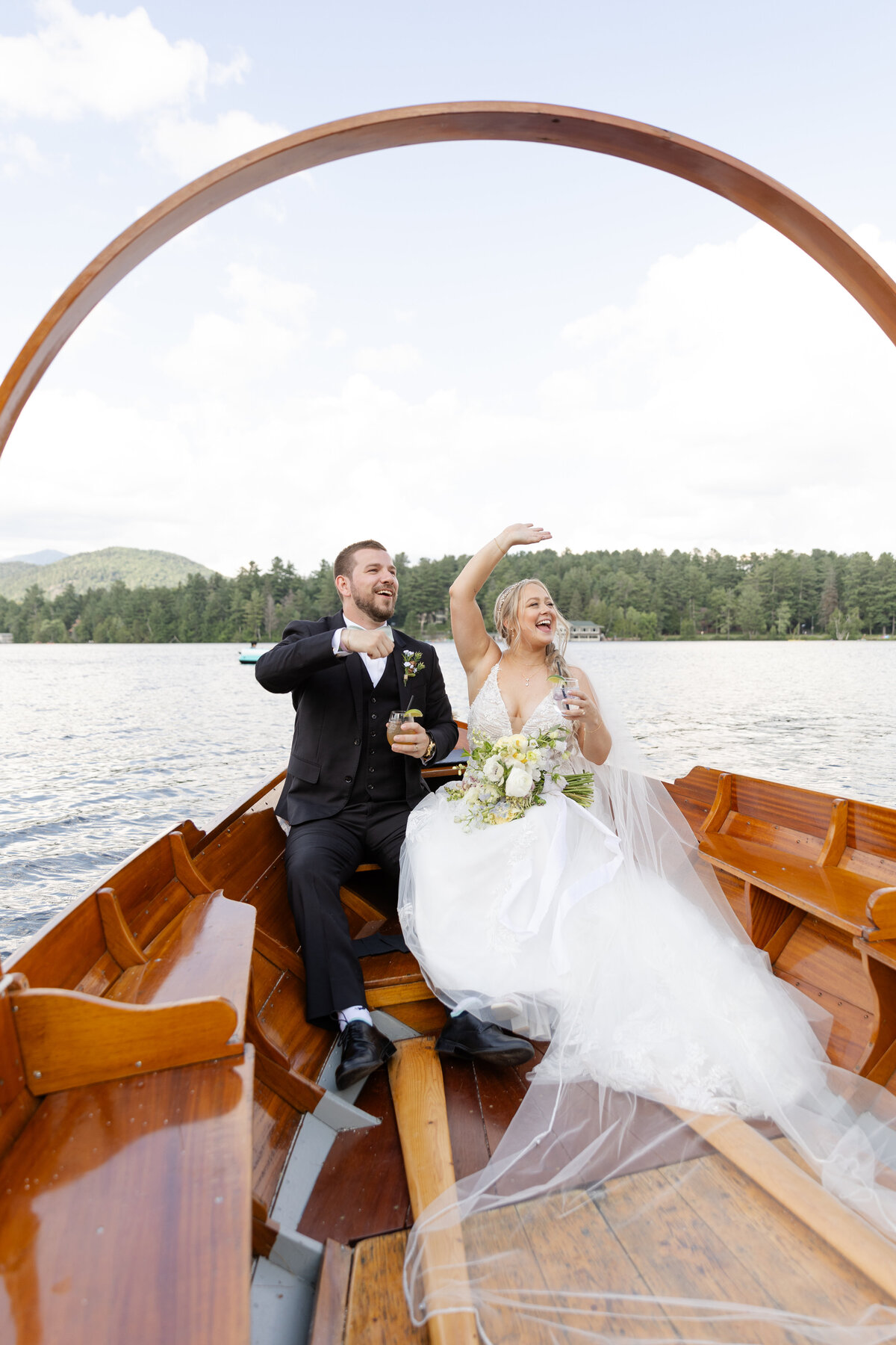 Bride and groom wave to their guests as they sail away on a boat