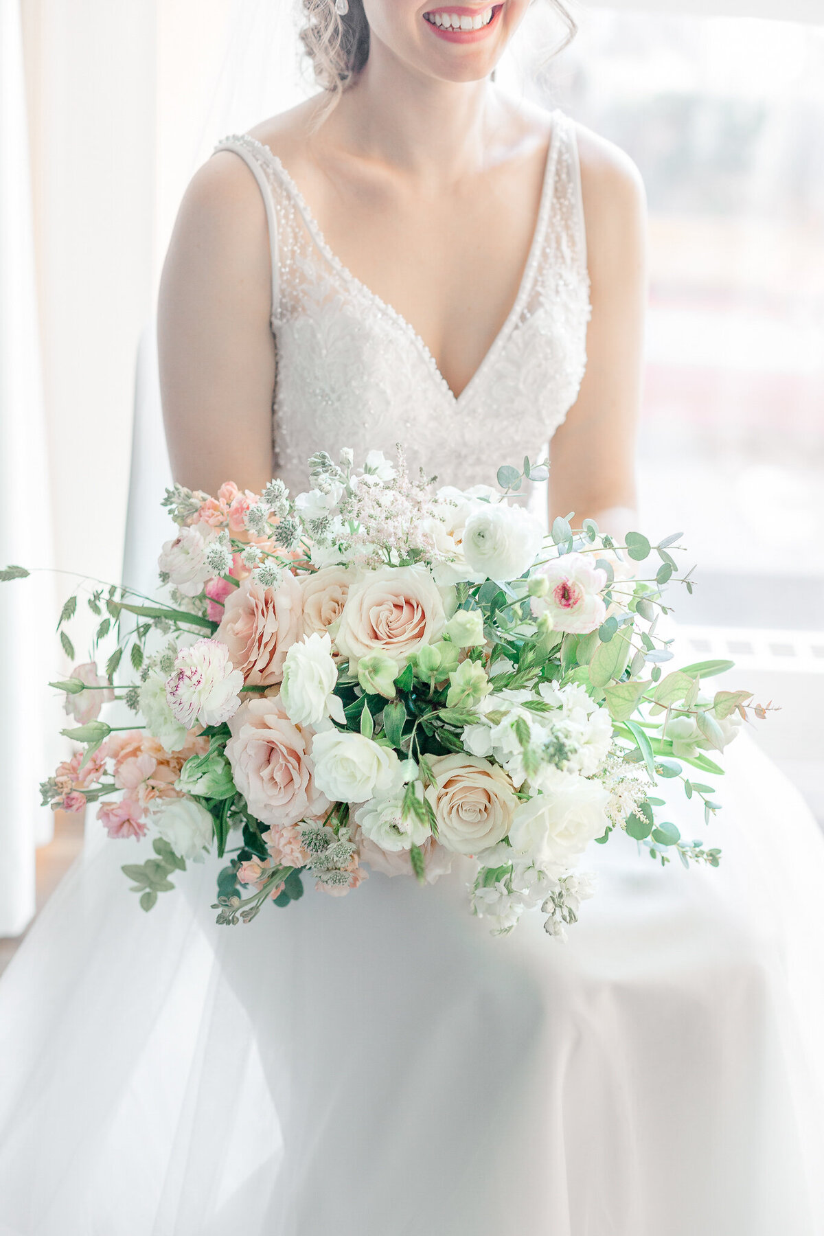 A bride holds a lush airy bouquet of pastel flowers at a Montreal wedding.