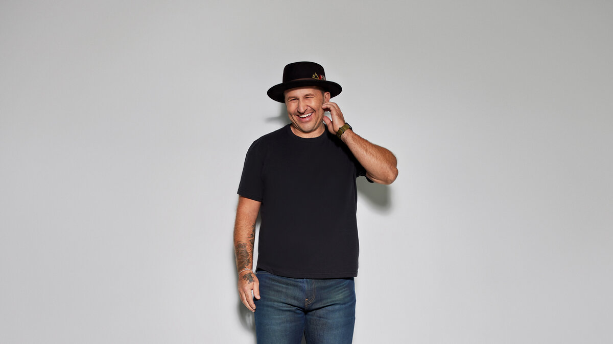 A man smiling and reaching one hand to his neck