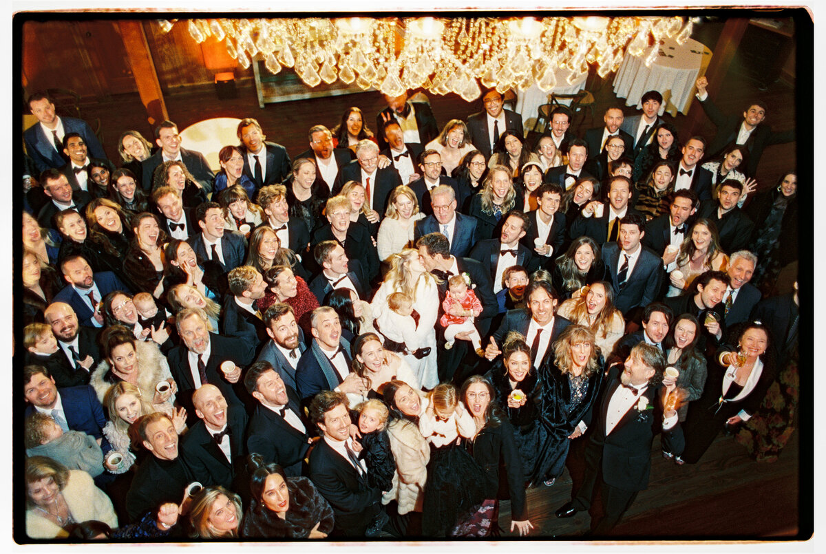 The wedding party gathered for a joyful group portrait, photographed on film in The wedding party gathered for a joyful group portrait, photographed on film in Carmel by Kate Winters