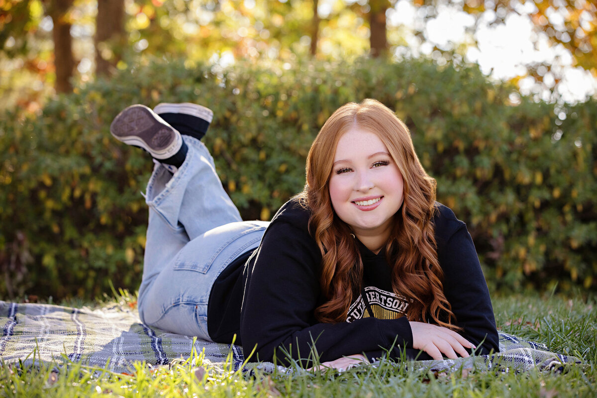 High school senior from South Charlotte laying on a blanket in a casual outfit during her senior portraits