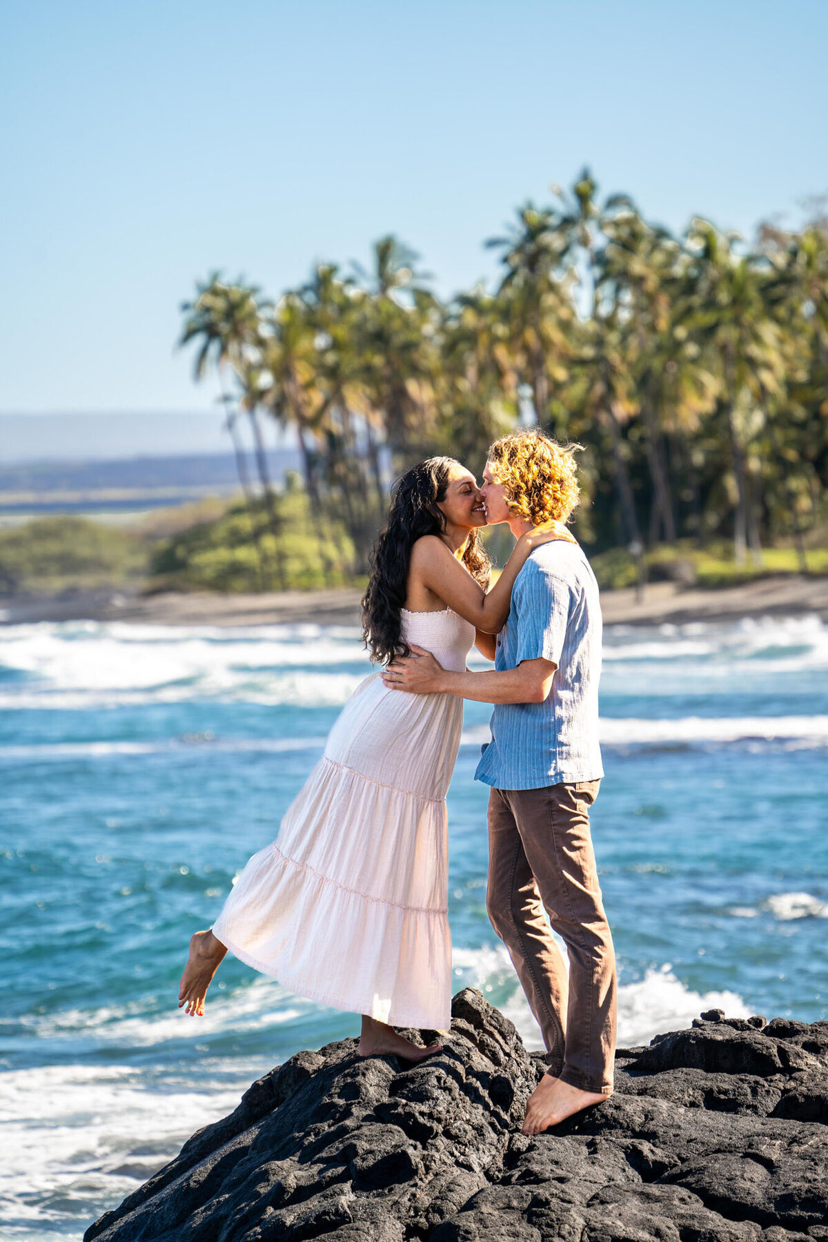 Couple kissing on lava rocks for Hawaii engagement photos