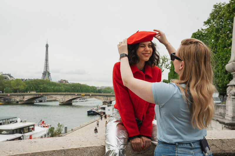Female is fixing the hat of a model, they are working on a photoshoot in Paris